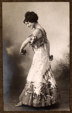 De perfil, con vestido bordado y castañuelas