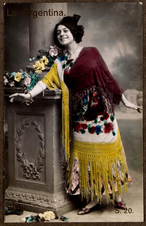 Apoyada en una columna del decorado, posando con un mantón de Manila de flores bordadas cubriendo el vestido