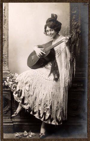 Sentada en una moldura del decorado, tocando la guitarra